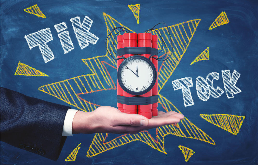 A hand holding a ticking time-bomb of red dynamite and a clock, drawn on a chalkboard